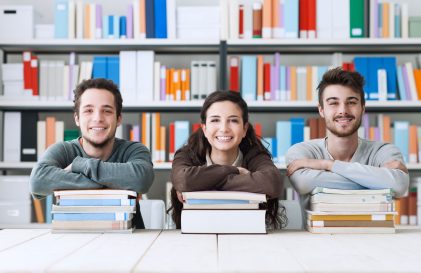 a group of people sitting at a table in front of books.