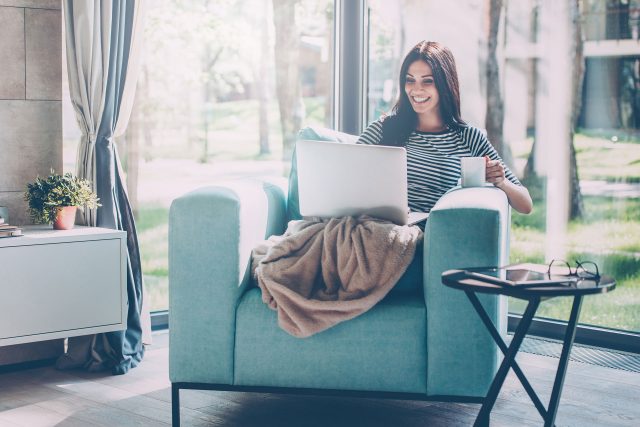 a woman sitting on a couch with a laptop.