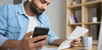 Man holding mobile phone to pay bill using mobile banking app.