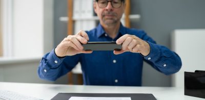 Man holding phone taking a picture of check for mobile deposit.